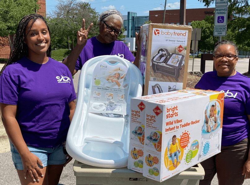 Solutions BY lynn volunteers holding donations of baby essentials free